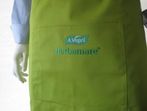 Bei dieser Latzschürze wurde eine besonders grosse, bestickte Tasche gewünscht. Die Stickerei beinhaltet das beworbene Produkt sowie den Firmennamen.
